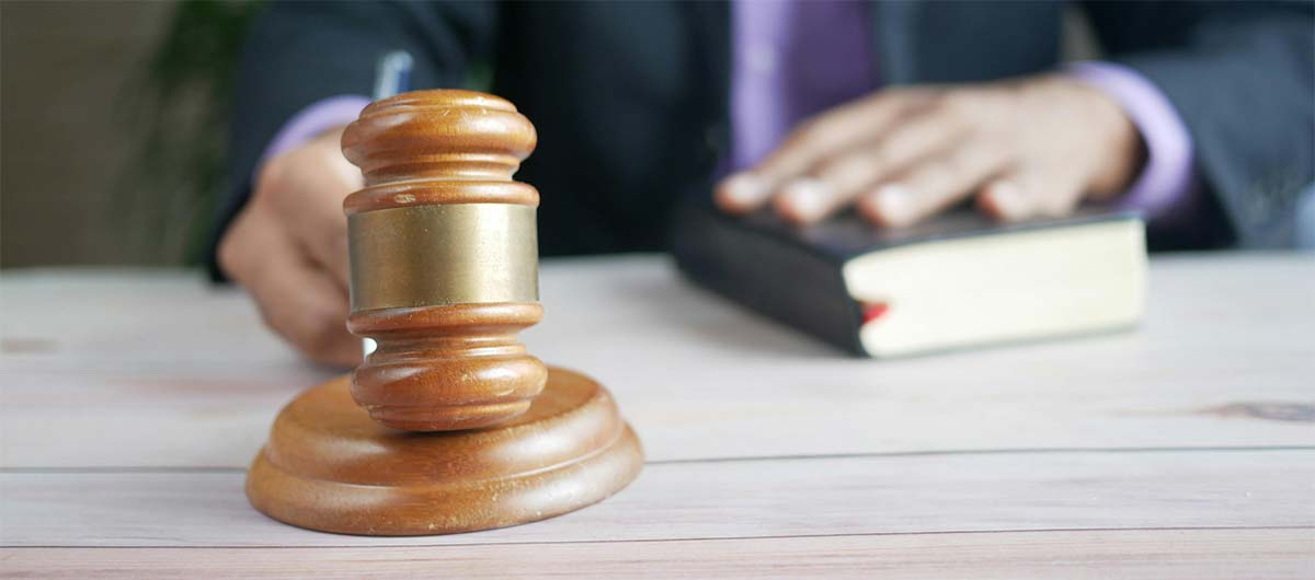 A person holding a gavel and placing their hand on a book