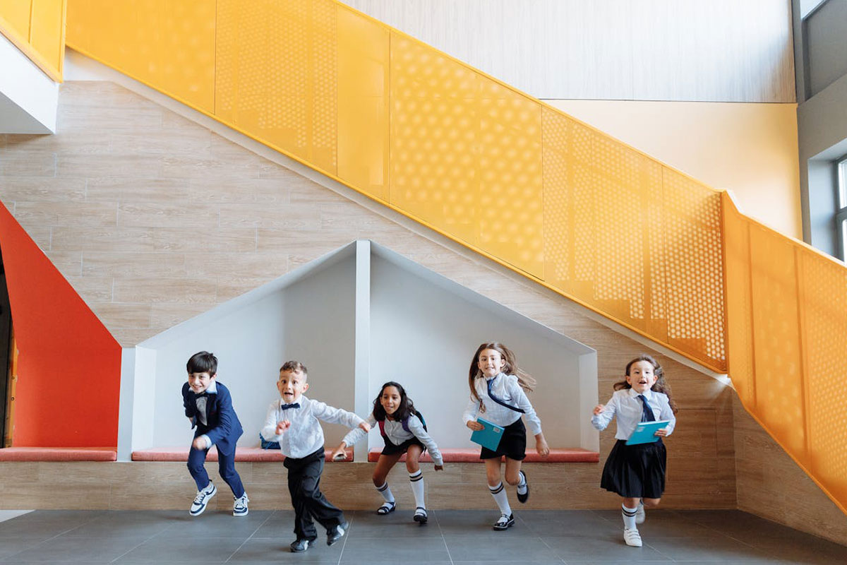 a group of young children running inside a school building