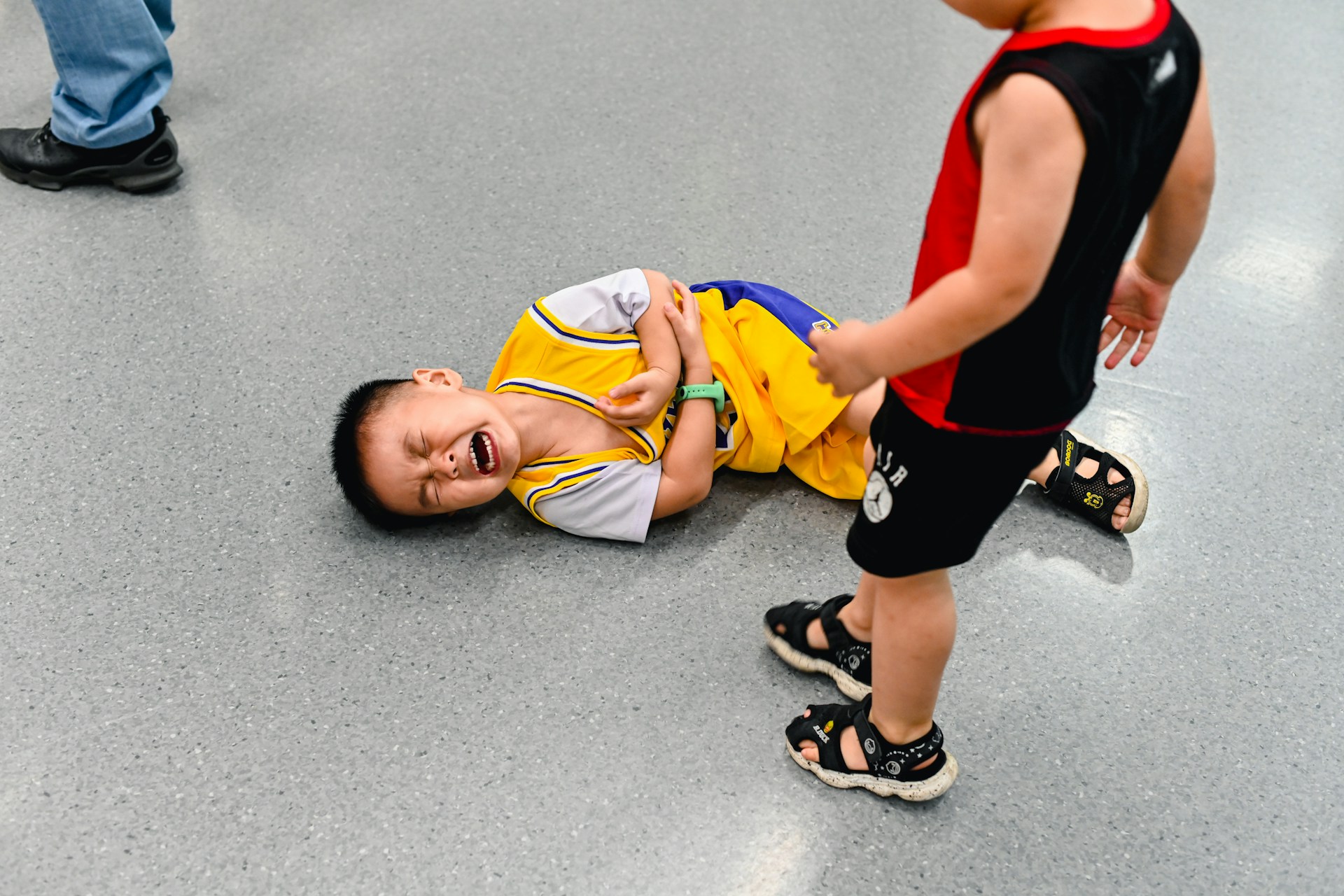 A child injured by another student, lying on the floor, crying