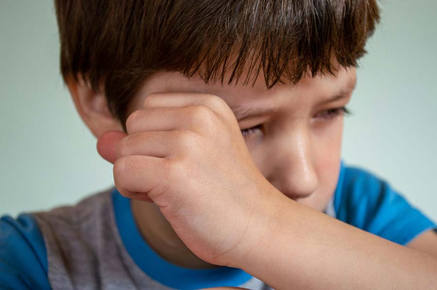 a close-up of a boy wiping his tears