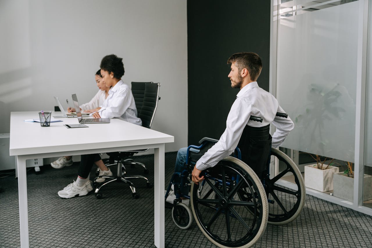 A person in a wheelchair with coworkers at an office table