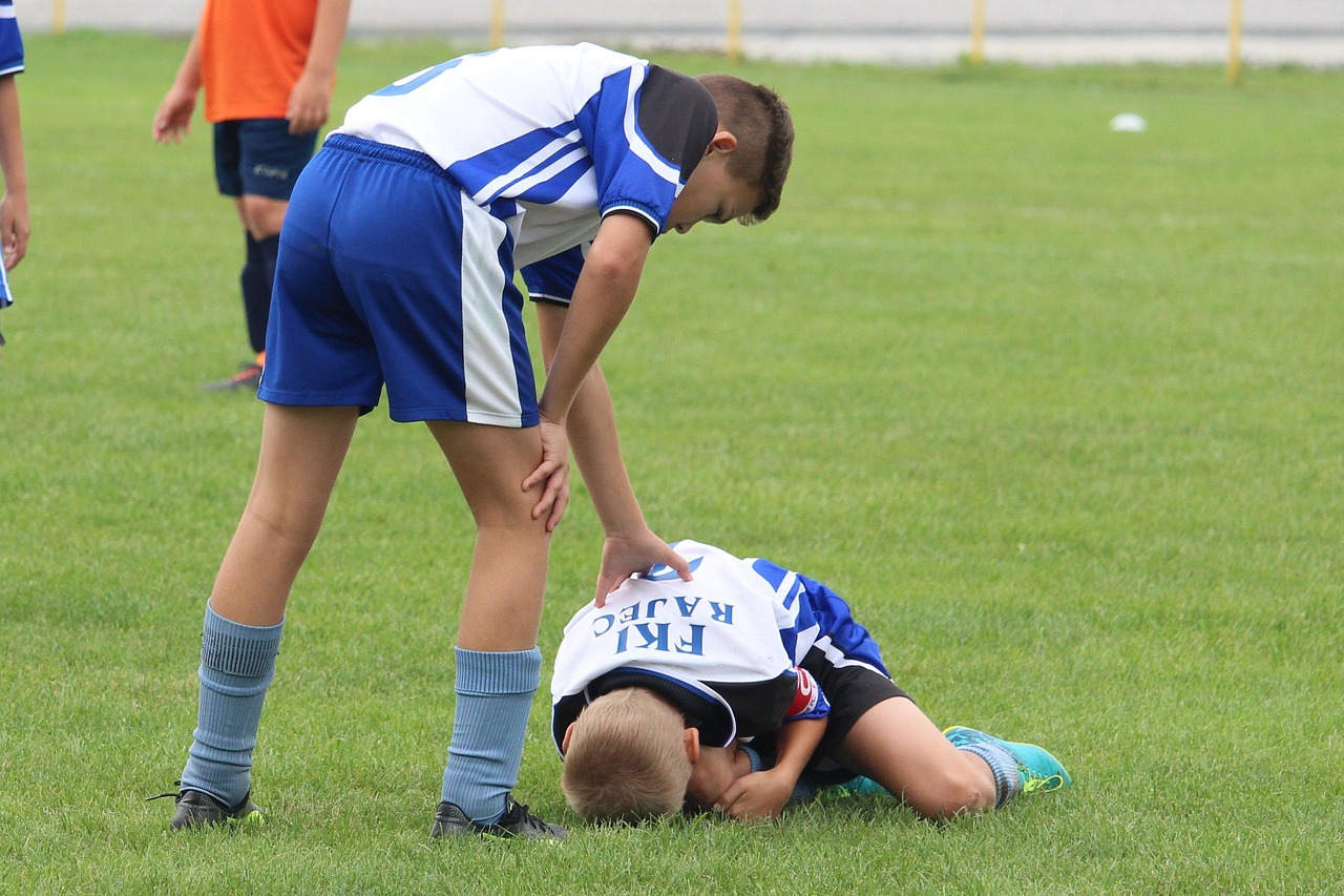 A teen student helping an injured teammate in a school playground