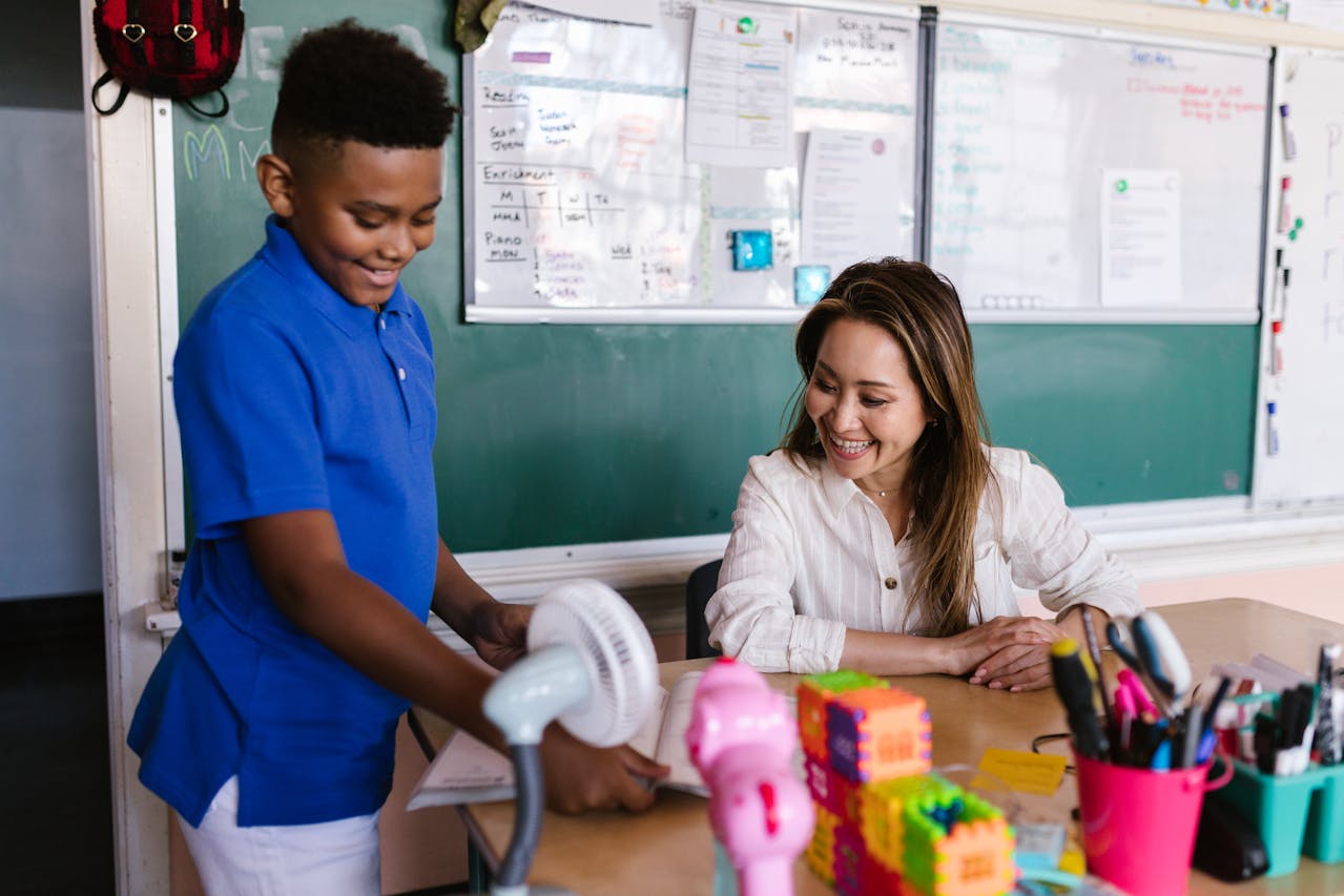 a happy student showing a book to a happy teacher