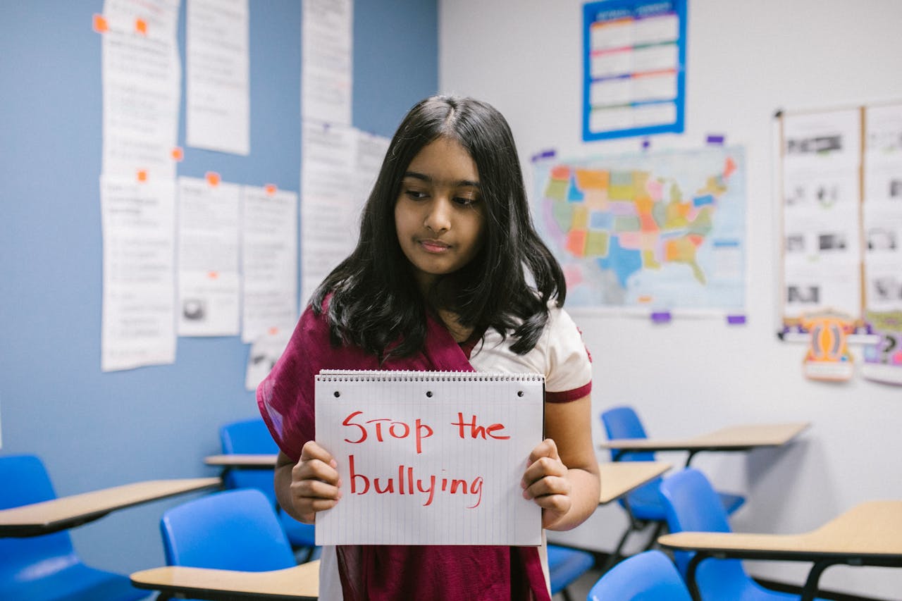a girl holding a book that reads “stop the bullying”
