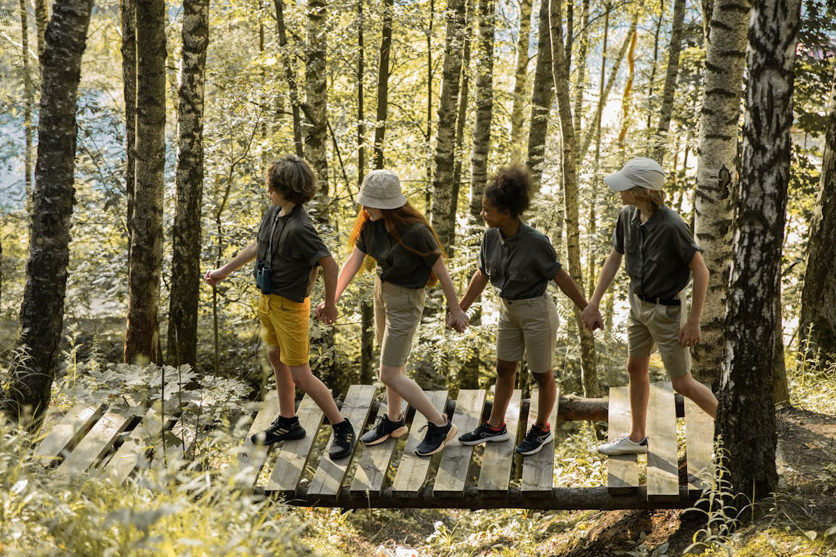 Teenagers holding hands while walking on a wooden bridge in a forest